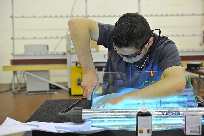 jeune homme avec lunette de protection penché sur son travail dans un atelier