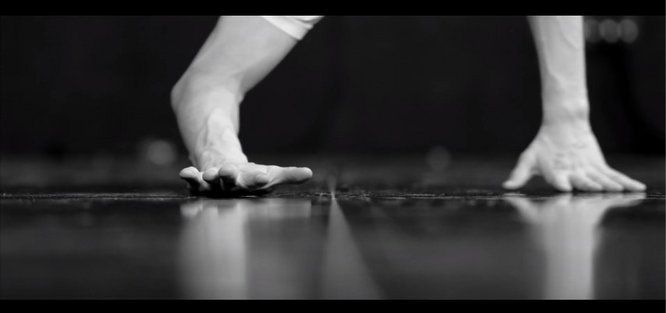 photo en noir et blanc plan resserré sur deux mains d'un danseur en équilibre sur scène